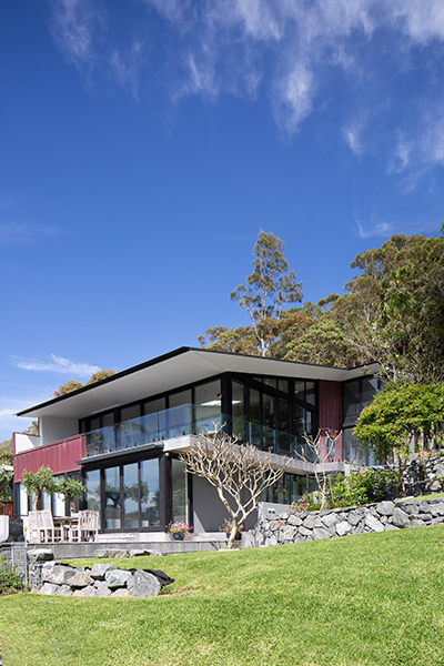 External view of the building on a green hill, black bushfire safe windows